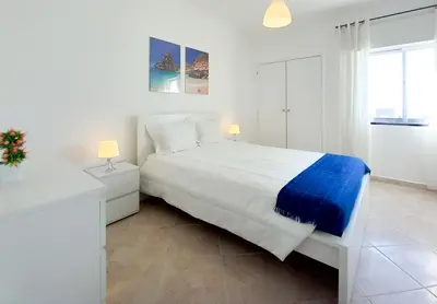 a white bedroom with a large bed and a window at T1 PonteMira 6 50M PRAIA VISTA MAR in Quarteira