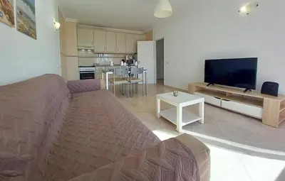 a living room with a couch and a flat screen tv at T1 PonteMira 6 50M PRAIA VISTA MAR in Quarteira