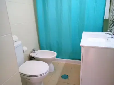 a bathroom with a toilet and a sink and a blue shower curtain at T1 Praiamar 4 Vista Magnifica in Quarteira