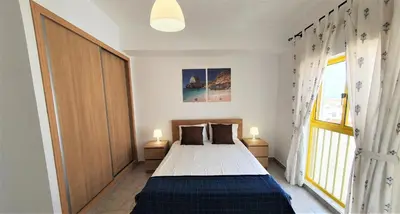 a bedroom with a bed and a large window at T1 Dunas 7 - Aconchegante, Wifi, 150mt Praia in Quarteira