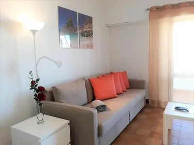 a living room with a couch with orange pillows at Torre 6- Vista Cidade, Aconchegante, 80mt Praia, Wifi in Quarteira