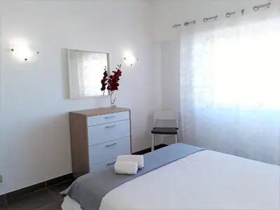 a bedroom with a bed and a dresser and a window at Torre 6- Vista Cidade, Aconchegante, 80mt Praia, Wifi in Quarteira