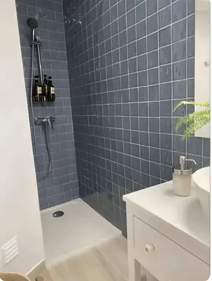 a blue tiled bathroom with a shower and a sink at Panoramic Faro Apartment in Faro