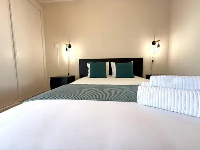 a bedroom with a large white bed with green pillows at Go4Portugal - Vilamagna - Luxe Condo with Pool, Airco and Seaview Balcony in Albufeira