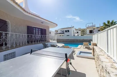 a balcony with a table and a swimming pool at Villa Brisa do Mar in Galé