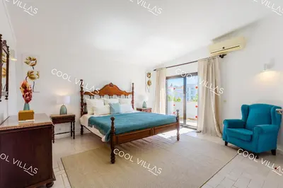 a bedroom with a bed and a blue chair at Villa Margarida - heatable pool & city center in Albufeira