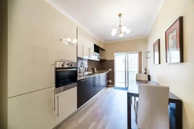 a kitchen with white cabinets and a table with a chair at Histórical City Center Penthouse Albufeira in Albufeira