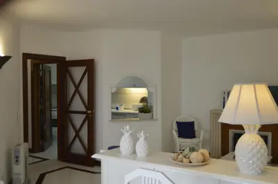 a living room with a table with a lamp and a mirror at Apartamento próximo da Marina Vilamoura c/piscina e estacionamento in Vilamoura