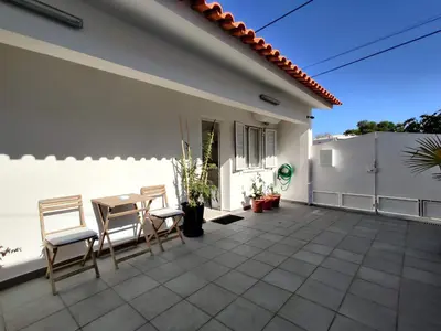a patio with chairs and a table and a white house at Casa Sequeira in Albufeira