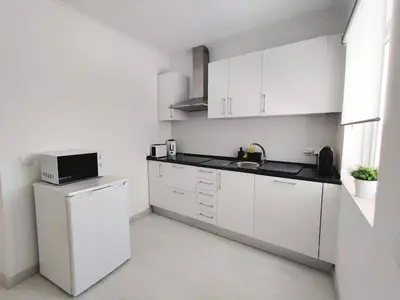 a white kitchen with a sink and a microwave at Casa Sequeira in Albufeira