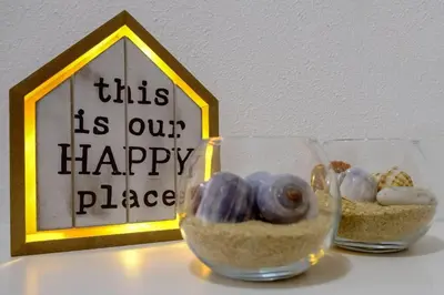 two glass vases filled with sand and rocks in front of a sign at AL-Dream Oura Estrela Apartments - CC in Albufeira