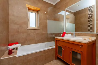 a bathroom with a sink and a tub and a mirror at Villa Florida by Algarve Vacation in Albufeira