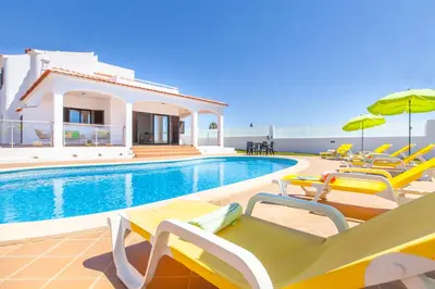 a pool with chairs and umbrellas next to a villa at Villa Abel by Algarve Vacation in Albufeira