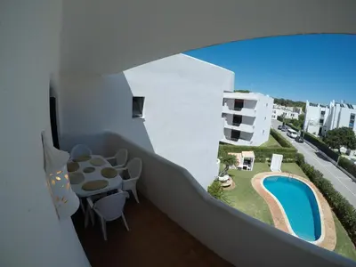a balcony with a table and a swimming pool at Casa de Vilamoura in Vilamoura