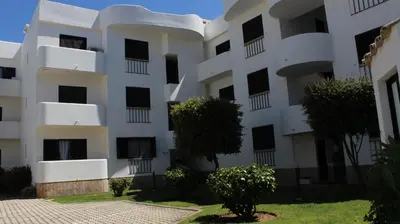 a white apartment building with trees in front of it at Casa de Vilamoura in Vilamoura