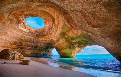 a large rock formation on a beach with the ocean at Villa Amendoeiras 52 in Albufeira