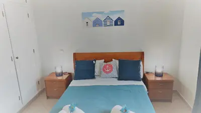 a bedroom with a bed with blue pillows and two night stands at 3 bedroom apartment in Oura Albufeira with amazing pool at walking distance to beach, strip and old town, WIFI and AC, private condo in Albufeira