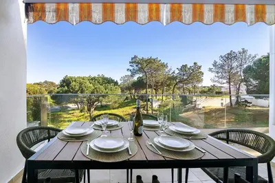 a wooden table with plates and a bottle of wine at Apartment Dansk in Almancil