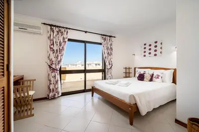 a bedroom with a bed and a large window at LovelyStay - Bela Vista 3BDR Duplex Penthouse with Pool in Albufeira