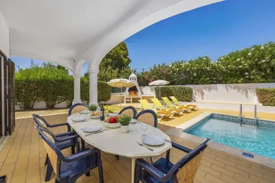 a villa with a swimming pool and chairs and a table at Villa Aldeia by Villa Plus in Albufeira