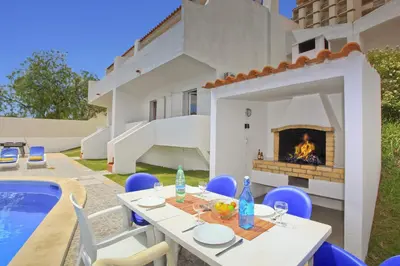 a patio with a table and a fireplace next to a house at Villa Altis Park by Villa Plus in Albufeira