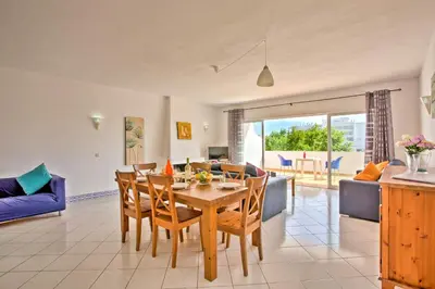 a dining room and living room with a table and chairs at Villa Altis Park by Villa Plus in Albufeira