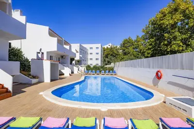 a swimming pool in a courtyard with chairs and a building at Villa Altis Park by Villa Plus in Albufeira