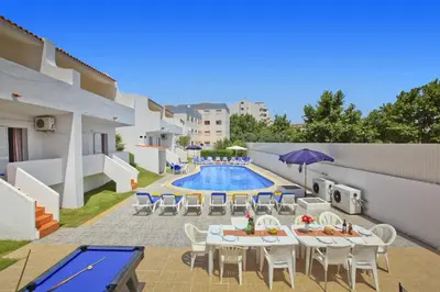 a patio with tables and chairs next to a swimming pool at Villa Altis Park by Villa Plus in Albufeira
