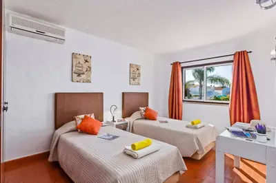 a hotel room with two beds and a window at Villa Emilio Pequena by Villa Plus in Albufeira