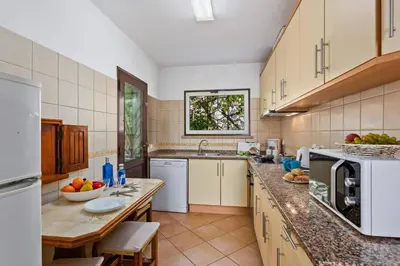 a large kitchen with white appliances and a wooden table at Villa Emilio Pequena by Villa Plus in Albufeira