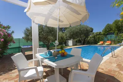 a table and chairs with an umbrella next to a swimming pool at Villa Emilio Pequena by Villa Plus in Albufeira