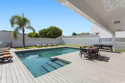 a patio with a table and chairs and a pool at Villa Eve by Villa Plus in Olhos de Água