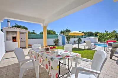 a table and chairs on a patio with a pool at Villa Miguel by Villa Plus in Galé