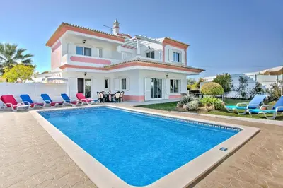 a villa with a swimming pool in front of a house at Villa Rosa by Villa Plus in Olhos de Água