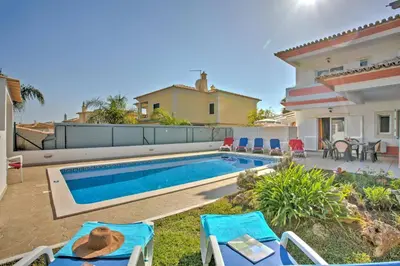 a patio with a table and chairs and a pool at Villa Rosa by Villa Plus in Olhos de Água