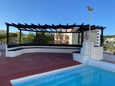 a swimming pool with a pergola next to a house at House Amendoeiras , Vila moura in Vilamoura