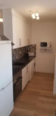 a kitchen with white cabinets and a black counter top at New Grand duplex avec terrasse plein sud vue piscine in Vilamoura
