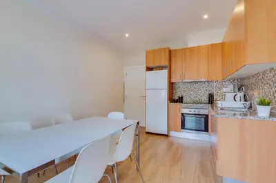 a kitchen with wooden cabinets and a white refrigerator at Quarteira 2Br - near the beach at Homesbyfc in Quarteira
