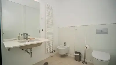 a white bathroom with a sink and a toilet at Central Vilamoura Townhouse in Quarteira