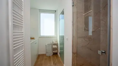 a bathroom with a walk in shower next to a window at Central Vilamoura Townhouse in Quarteira