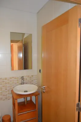 a bathroom with a sink and a wooden door at Apartamento frente ao mar com piscina de água salgada in Quarteira