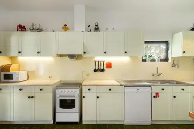 a kitchen with white cabinets and a white stove top oven at WHome | Balaia 3-Bed Family Holiday Villa in Olhos de Água