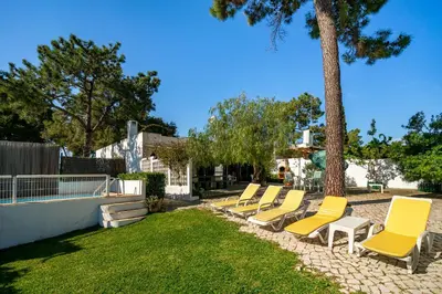 a row of yellow lounge chairs next to a tree at WHome | Balaia 3-Bed Family Holiday Villa in Olhos de Água