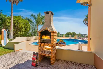 a brick oven is sitting next to a pool at Villa Nenufa by Villa Plus in Albufeira