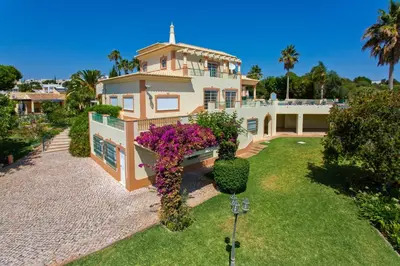 a large house with flowers in the yard at Villa Nenufa by Villa Plus in Albufeira
