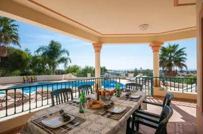 a dining table on a balcony with a view of a pool at Villa Nenufa by Villa Plus in Albufeira