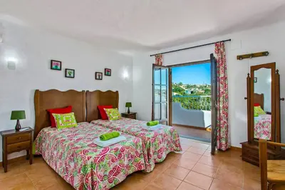 a bedroom with a large bed and a balcony at Villa Casa do Laguinho by Villa Plus in Albufeira