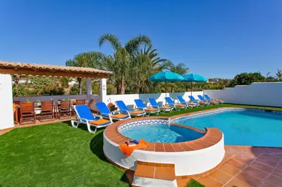 a patio with chairs and a swimming pool with a deck at Villa Casa do Laguinho by Villa Plus in Albufeira