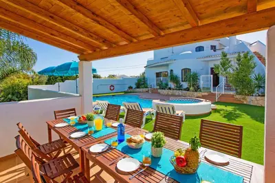 a patio with a table and chairs and a pool at Villa Casa do Laguinho by Villa Plus in Albufeira