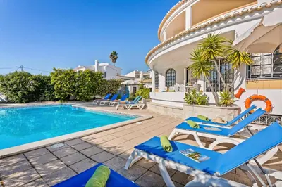 a villa with a swimming pool and blue chairs at Villa Aldeia Cristina by Villa Plus in Albufeira